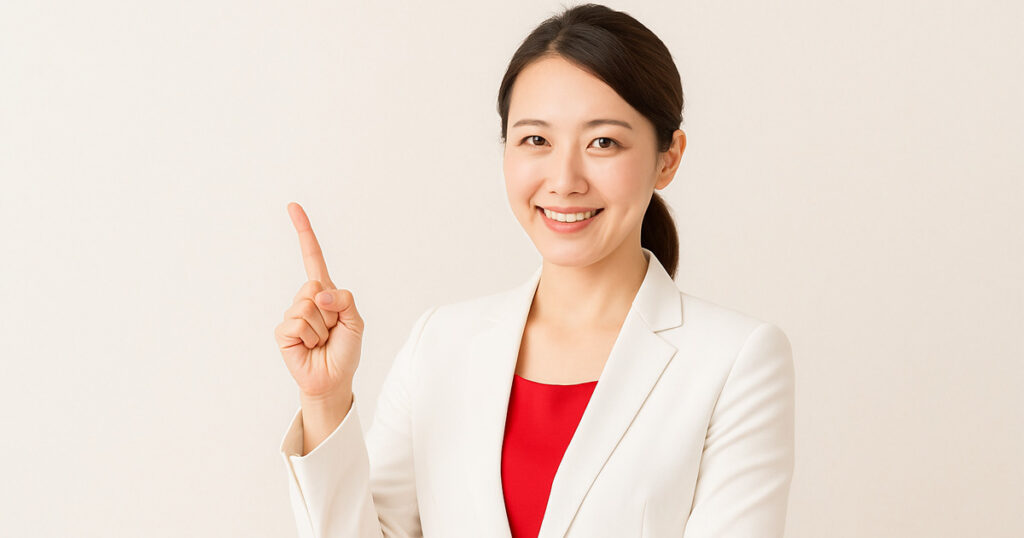 白いジャケットに明るい赤のインナーを着た日本人女性が、髪を後ろで結び、笑顔で指を立てている写真。背景は柔らかなベージュトーン。